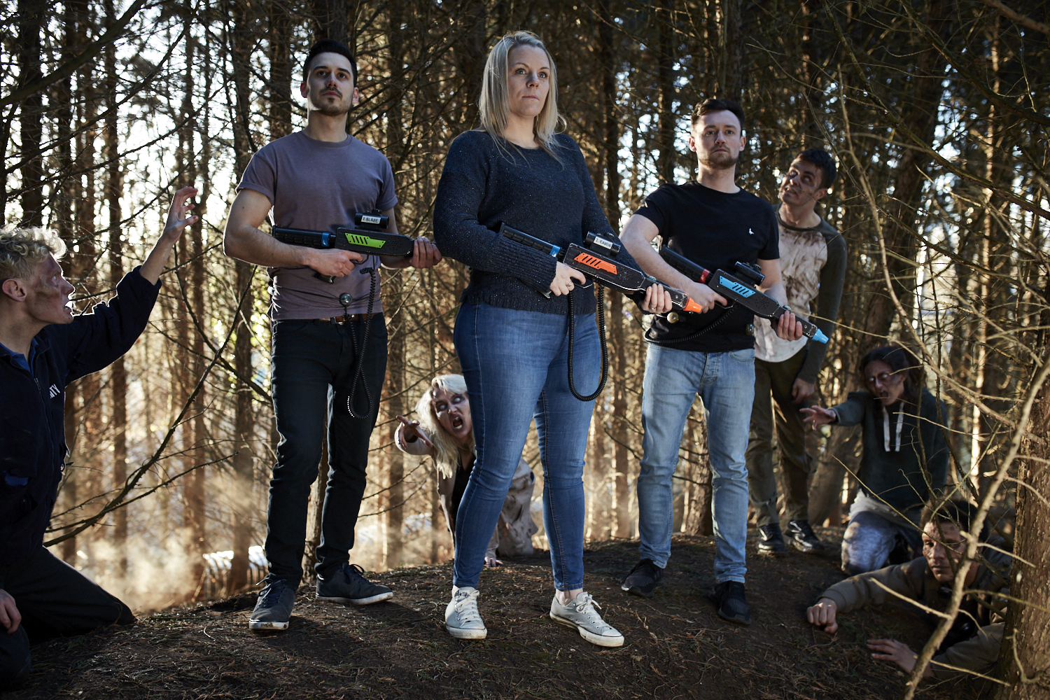 Zombie Hunt, group standing ready with guns and zombies lurching towards them