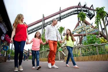 Family Walking Through Jungle Area Of The Theme Park