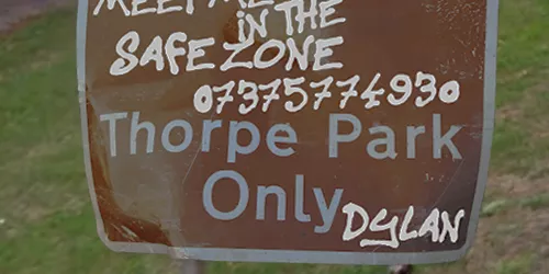 Road sign reading : Meet Me in the safezone 07375774930. Thorpe Park Only. Written by someone called Dylan