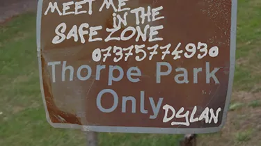 Road sign reading : Meet Me in the safezone 07375774930. Thorpe Park Only. Written by someone called Dylan