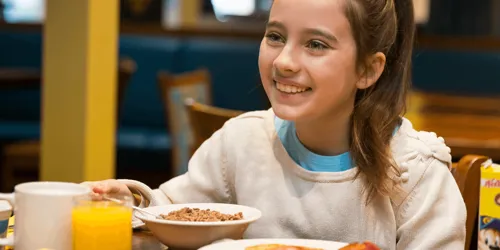 Girl sat at a table eating breakfast